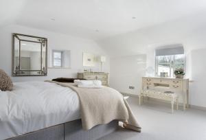 a white bedroom with a bed and a mirror at Mole End Cottage in North Cerney