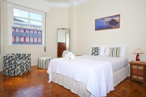 una camera bianca con un letto e una sedia di Unhotel - Apartamento de Temporada em Ipanema com 4 quartos a Rio de Janeiro