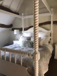 um quarto com uma cama branca e um poste de madeira em Mansfield Cottage em Kilsby
