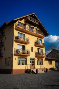 a yellow building with balconies on the side of it at Pensiunea Riffelt in Bran