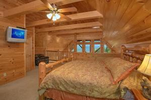 um quarto num chalé de madeira com uma cama e uma televisão em Splash Mansion #500 em Gatlinburg