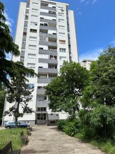 un edificio alto y blanco con árboles delante en One bedroom apartment in great location, en Podgorica