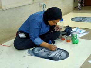 a woman sitting on the floor painting a fish on the floor at بيت الشباب الاسماعيلية - Ismailia Youth Hostel in Ismailia
