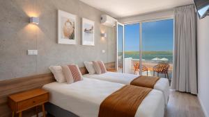 ein Hotelzimmer mit 2 Betten und einem großen Fenster in der Unterkunft Hotel Made inn Faro in Faro