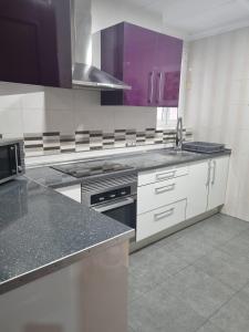 una cocina con electrodomésticos blancos y armarios morados en Habitación Villena lavanda, en Villena