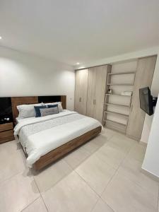 1 dormitorio con 1 cama grande y TV en Apartamentos Loft Mikonos, en Pereira