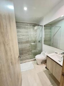 y baño con aseo y ducha acristalada. en Apartamentos Loft Mikonos, en Pereira