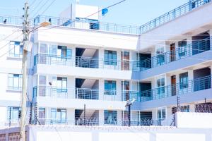 a white building with blue balconies on it at Pearl Suites and Hospitality in Bungoma