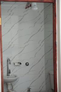 een badkamer met een wastafel en een witte marmeren muur bij Pearl Suites and Hospitality in Bungoma