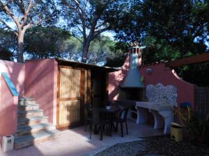 eine Terrasse mit einem Kamin, einem Tisch und Stühlen in der Unterkunft S'Arena in Cala Liberotto