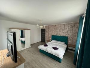 Schlafzimmer mit einem Bett, einem TV und einem Spiegel in der Unterkunft Kul House - Cazare in Băileşti