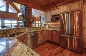 La cuisine est équipée d'armoires en bois et d'un réfrigérateur en acier inoxydable. dans l'établissement Majestic View Lodge #426, à Sevierville
