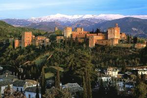 a large castle on a hill with snow covered mountains at Ático con vistas a Sierra Nevada in Armilla