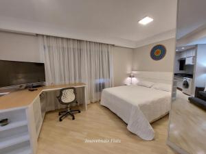 a bedroom with a bed and a desk with a television at Bienal Ibirapuera in Sao Paulo