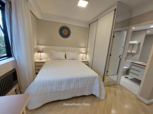 um quarto com uma cama branca e um espelho em Bienal Ibirapuera em São Paulo