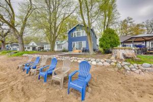 a row of blue chairs in the sand in front of a house at Lakefront Burlington Vacation Rental Dock and Beach in Twin Lakes