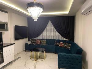 een woonkamer met een blauwe bank en een kroonluchter bij Fully furnished 1+1 apartment in luxury complex Heaven Hills in Mahmutlar