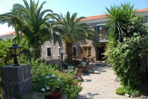 a courtyard with palm trees and a building at Hotel Adonis in Mithymna