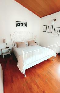 1 cama blanca en un dormitorio blanco con suelo de madera en Aurora Appartamenti, en Negrar