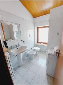 La salle de bains blanche est pourvue d'un lavabo et de toilettes. dans l'établissement Aurora Appartamenti, à Negrar