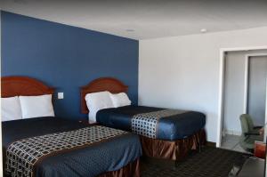 Economy Inn في Ada: غرفه فندقيه سريرين وجدار ازرق