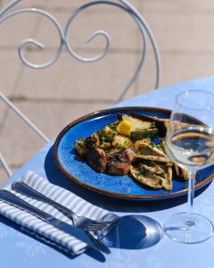 un piatto di cibo su un tavolo con un bicchiere di vino di Hôtel de la Plage a Excénevex