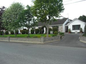 a house with a stone fence in front of a driveway at Fortview House in Cavan