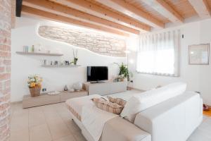 een woonkamer met een witte bank en een tv bij Una Chicca in Valdobbiadene