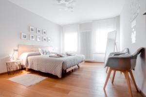 a white bedroom with a bed and a chair at Una Chicca in Valdobbiadene