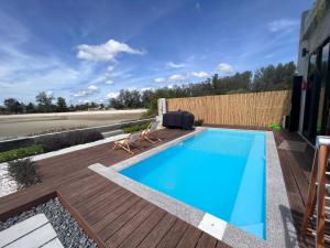 una piscina con terraza de madera y piscina en Ocean Nadi 4 Bedrooms Beachfront Villa PD, en Port Dickson