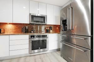 マイアミにあるRoami at Brickell Penthouse Urban Retreatのキッチン(白いキャビネット、ステンレス製の冷蔵庫付)