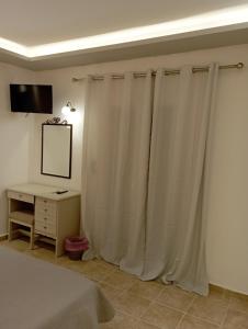 a bedroom with white curtains and a desk and a bed at Olive house in Marathias