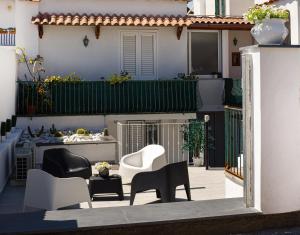 eine Terrasse mit Stühlen und einem Tisch vor einem Haus in der Unterkunft Variopinto Home in Ischia