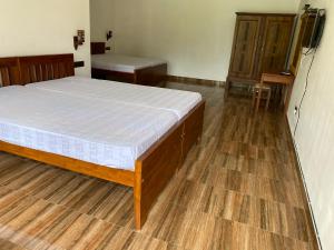 Schlafzimmer mit einem Bett und Holzboden in der Unterkunft 贝鲁沃勒中国民宿 in Ambepitiya