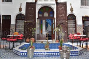 a courtyard with a pool in a building with tables and chairs at Dar Al Batoul in Fès