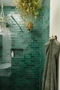 y baño con ducha de azulejos verdes y toalla. en Casa da Aldeia - Small House Selva - Peniche - Baleal en Casais Brancos