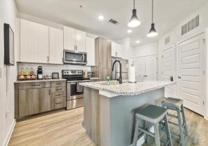 a kitchen with white cabinets and a counter with two stools at Luxurious 1 Bedroom Apartment Near Braves Stadium in Atlanta