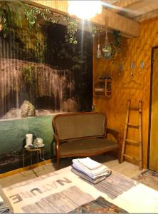 a room with a chair and a painting of a waterfall at Chambre d'hôte txaleta (le Chalet) in Saint-Priest-sous-Aixe