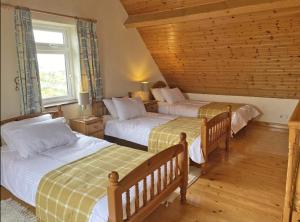 a bedroom with two beds and a window at Lands End Cottage - Connemara in Aughrus More