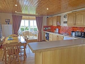 a kitchen with wooden cabinets and a table and a dining room at Lands End Cottage - Connemara in Aughrus More
