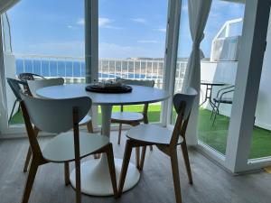 a table and chairs in a room with a balcony at Axenic Retreat - Panoramic Ocean View, Private Terrace, Sleeps 4, Ensuite Bathroom, New Redesign in Sesimbra