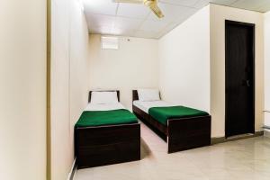 two beds with green cushions in a room at SPOT ON Panchavati Residency in Secunderabad