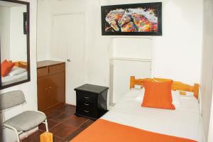1 dormitorio con cama, espejo y silla en Hotel BogoSuba 127, en Bogotá