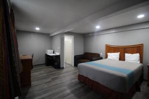 a hotel room with a bed and a chair at Starlite Motel in San Bernardino