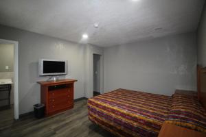 サンバーナーディーノにあるStarlite Motelのベッドルーム(ベッド1台、ドレッサー内のテレビ付)