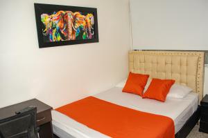 a bedroom with a bed with an orange blanket at Hotel BogoSuba 127 in Bogotá