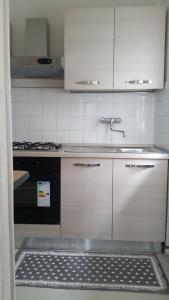 a kitchen with white cabinets and a stove and a rug at Apartment Iseo Lake in Sale Marasino