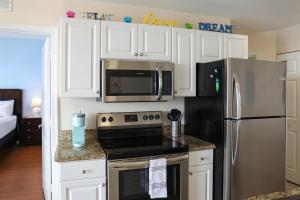 a kitchen with white cabinets and a stainless steel refrigerator at Dolphin Bay in Boca Ciega Resort - 2BR, Pool, Bay View in St. Petersburg