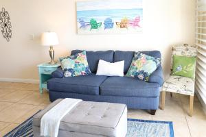 a living room with a blue couch and a table at Dolphin Bay in Boca Ciega Resort - 2BR, Pool, Bay View in St Petersburg