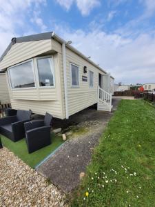 a mobile home with two chairs and a yard at 188 Holiday Resort Unity Brean - Central Location Pet Stays Free - Passes included No workers sorry in Brean
